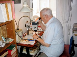Joaquim Mateu l’any 2005 assegut davant de la seva lupa binocular al laboratori que va instal·lar al seu pis del carrer Còrsega. Foto: Lluís Auroux.